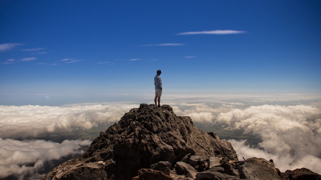 Persona en la cima de una montaña sobre un mar de nubes